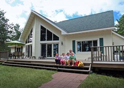 Exterior of house with large windows with family sitting on steps